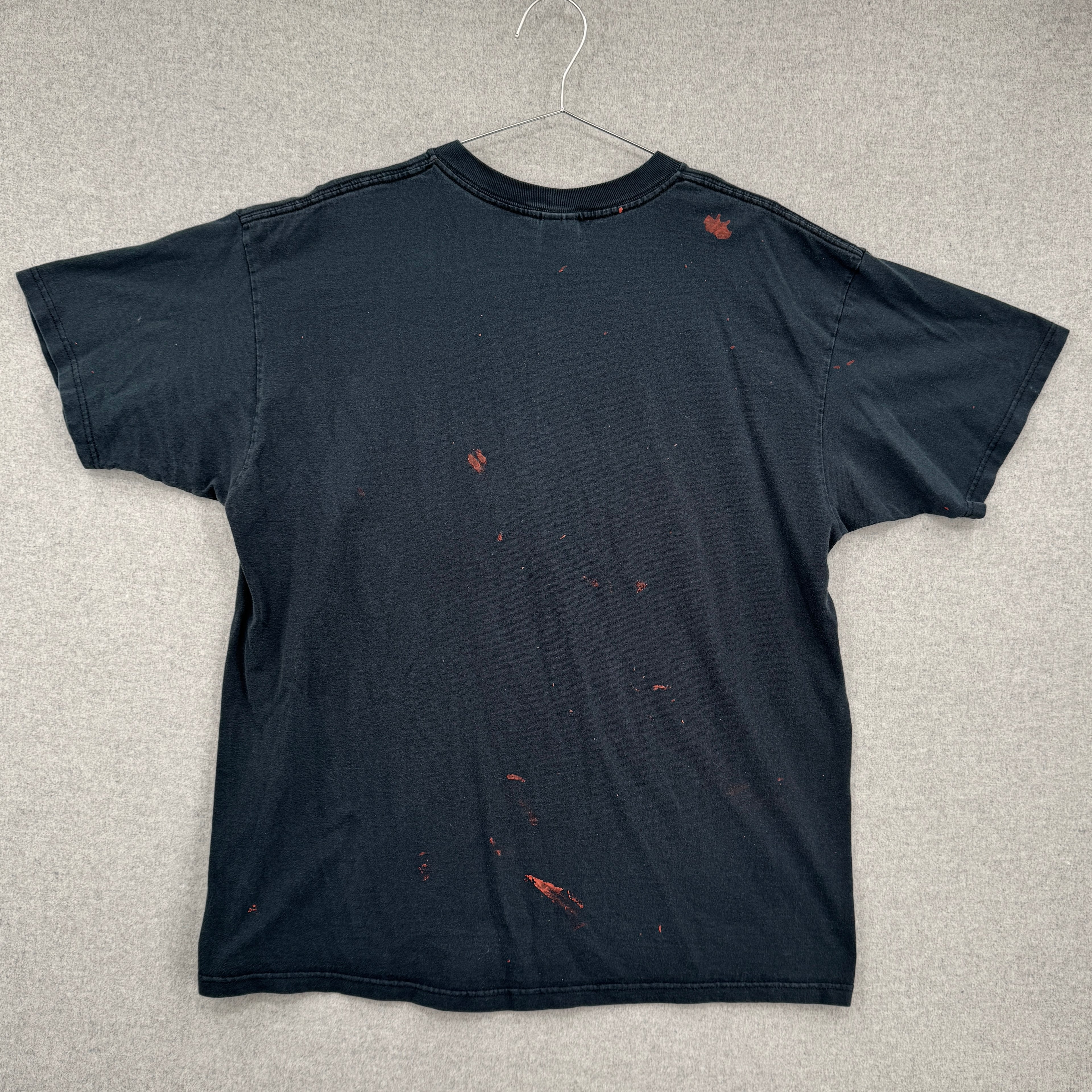 back of black tee shirt showing multiple red splatter stain spots