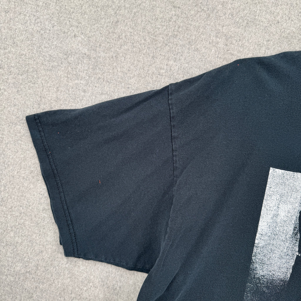 black shirt with a small red stain spot on the sleeve.