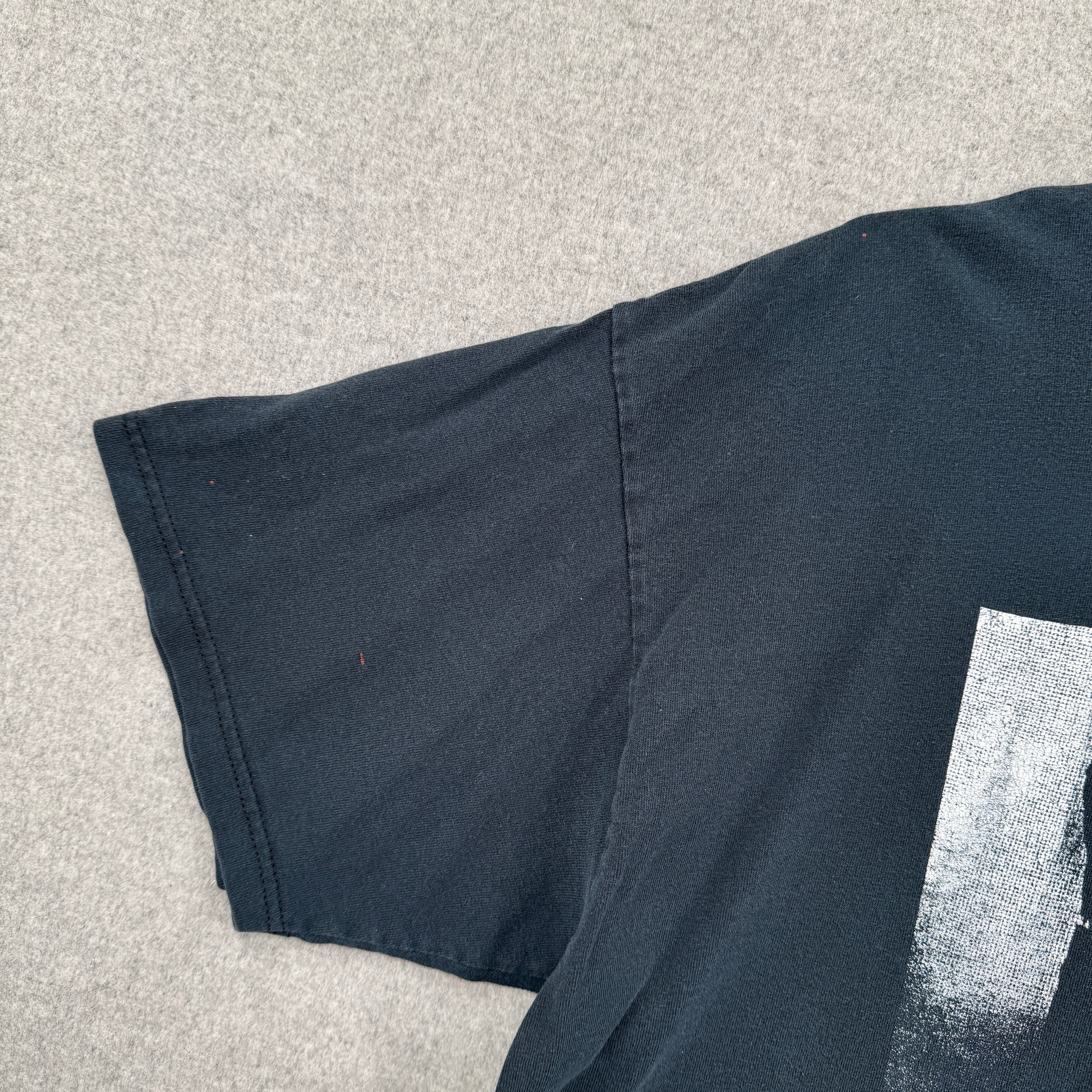black shirt with a small red stain spot on the sleeve.