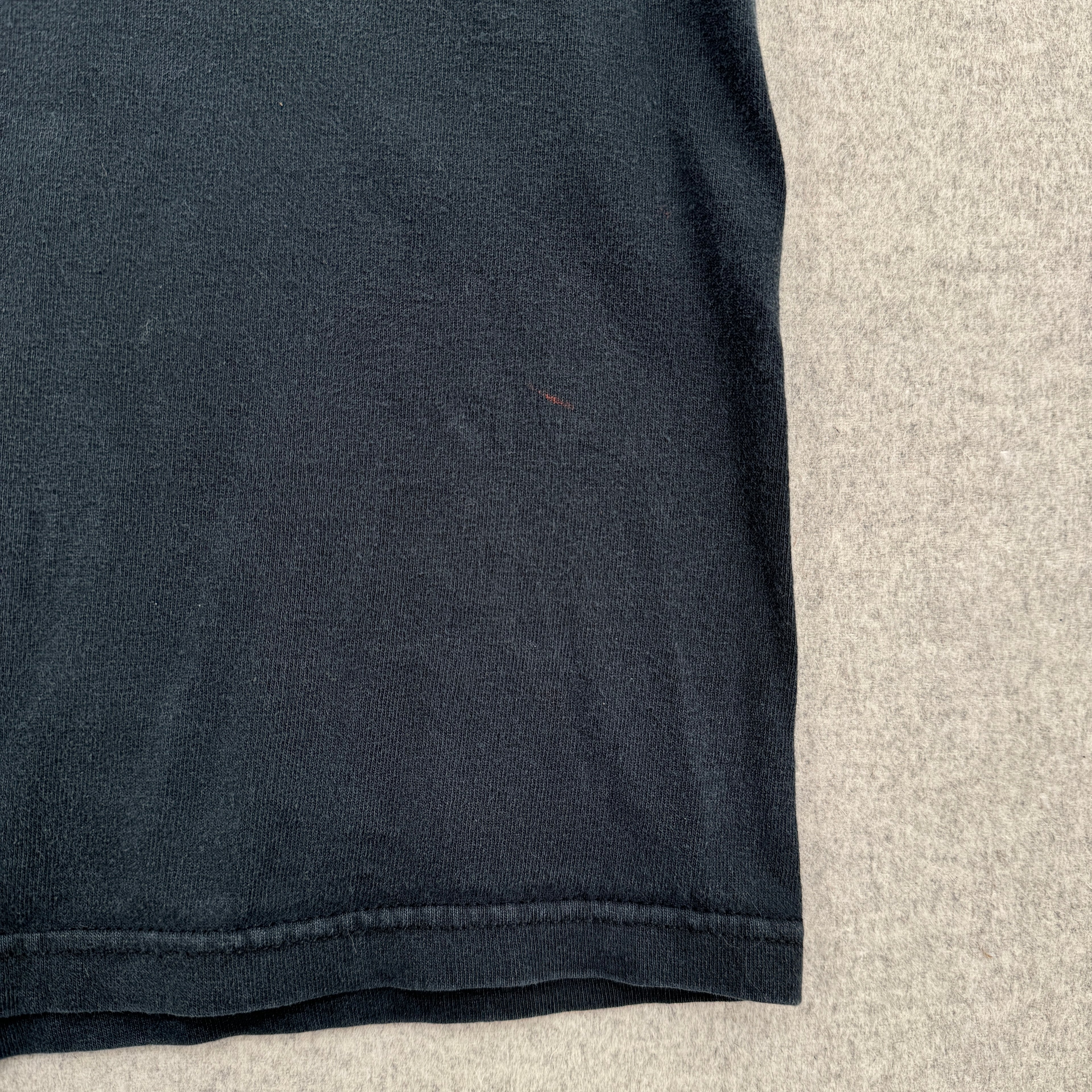 bottom of black shirt showing small red pen stain spot